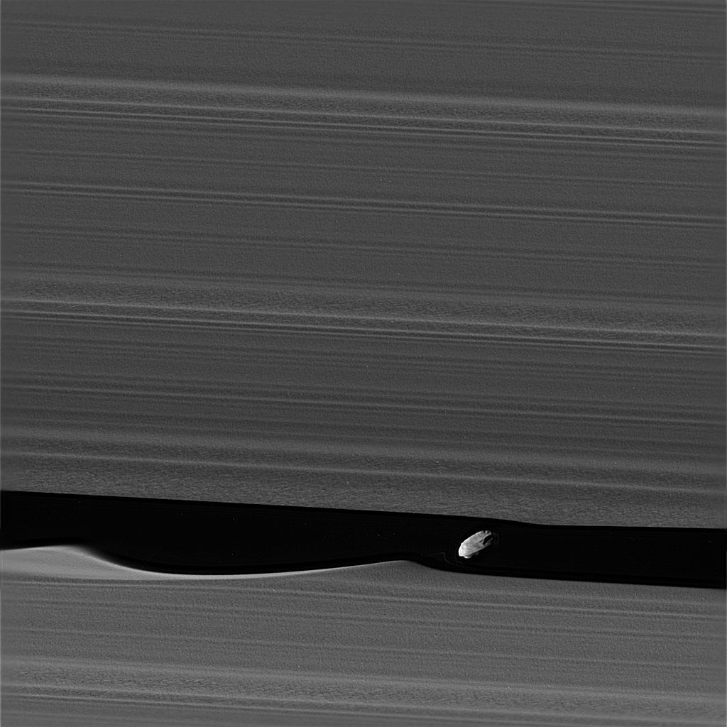 Black and white image of Daphnis among the rings of Saturn.