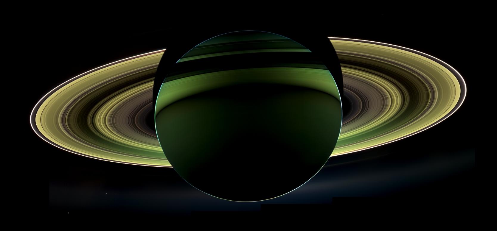 An image of a backlit, green-colored Saturn