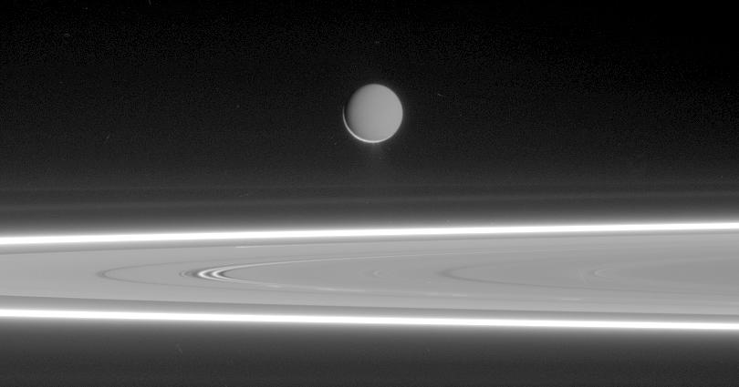 B&amp;W photo of Enceladus over Saturn's rings