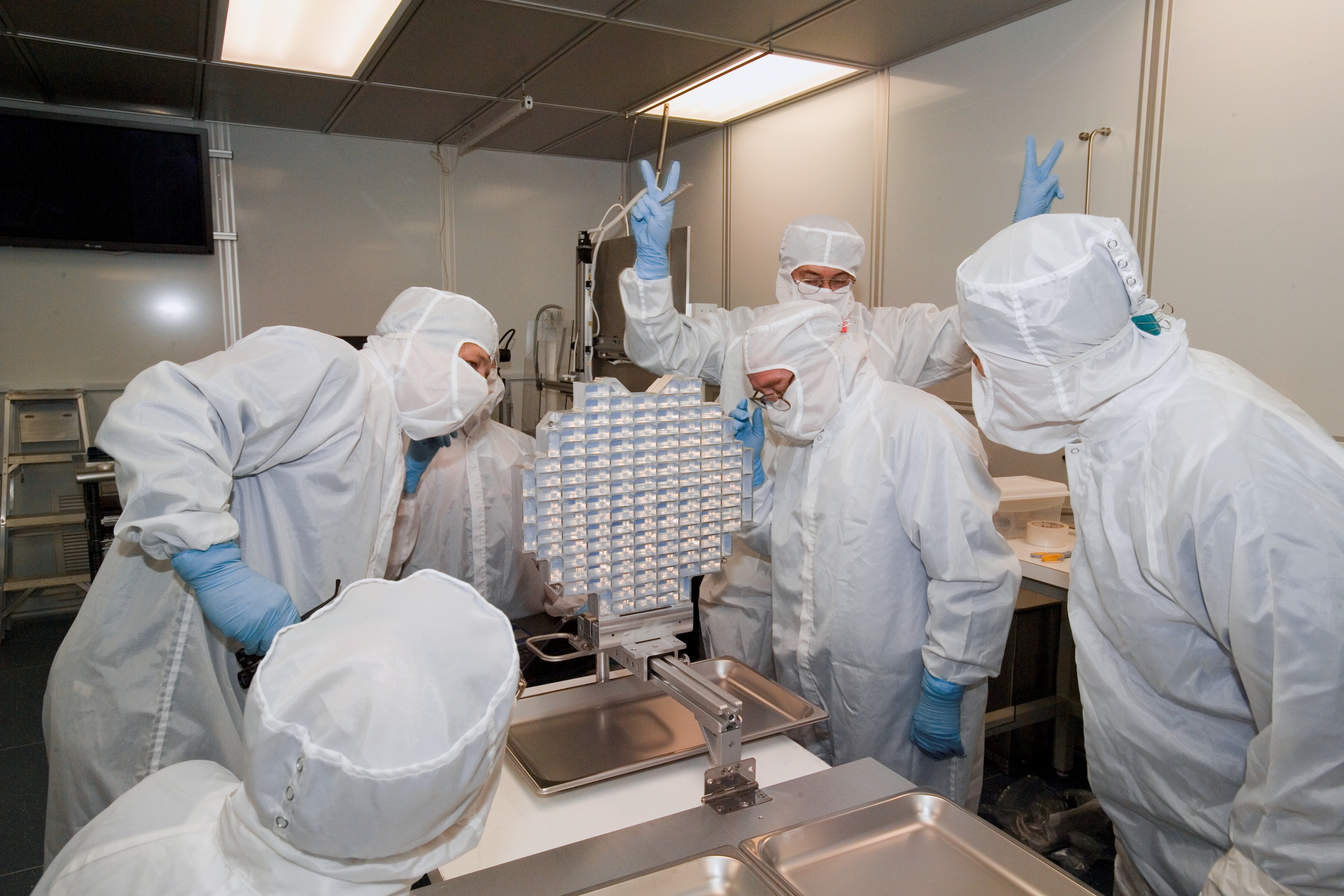Five people in protective gear looking at Stardust sample collector.