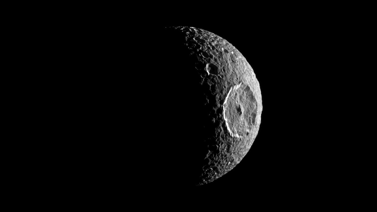 Moon with giant impact crater on its side.