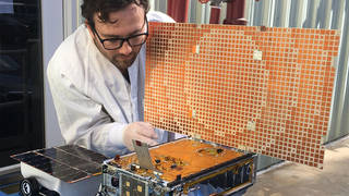 Man working on small spacecraft.