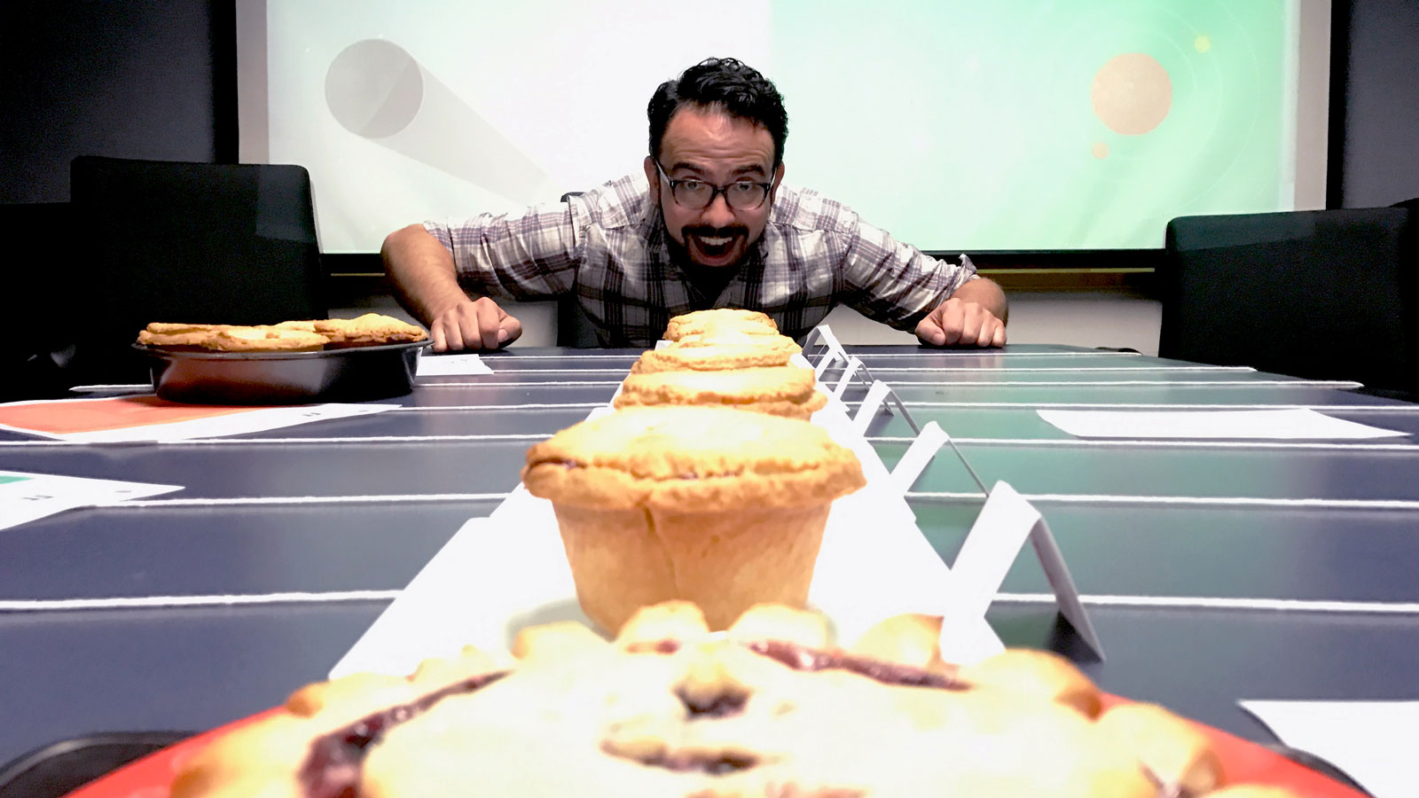 Smiling man with a beautiful row of tasty pies.