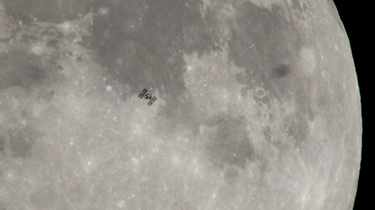 International Space Station in silhouette in front of the Moon.