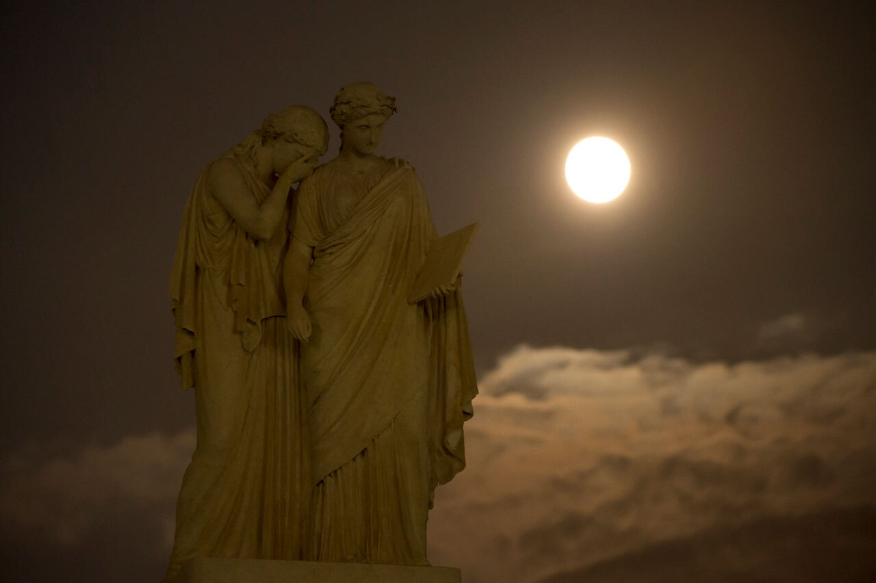 Bright moon with statues in foreground.