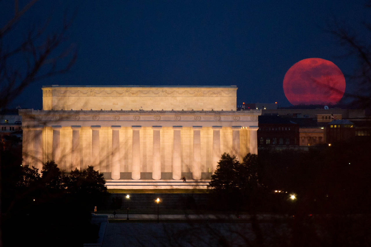 Reddish Moon rises next to Lincoln Memorial.