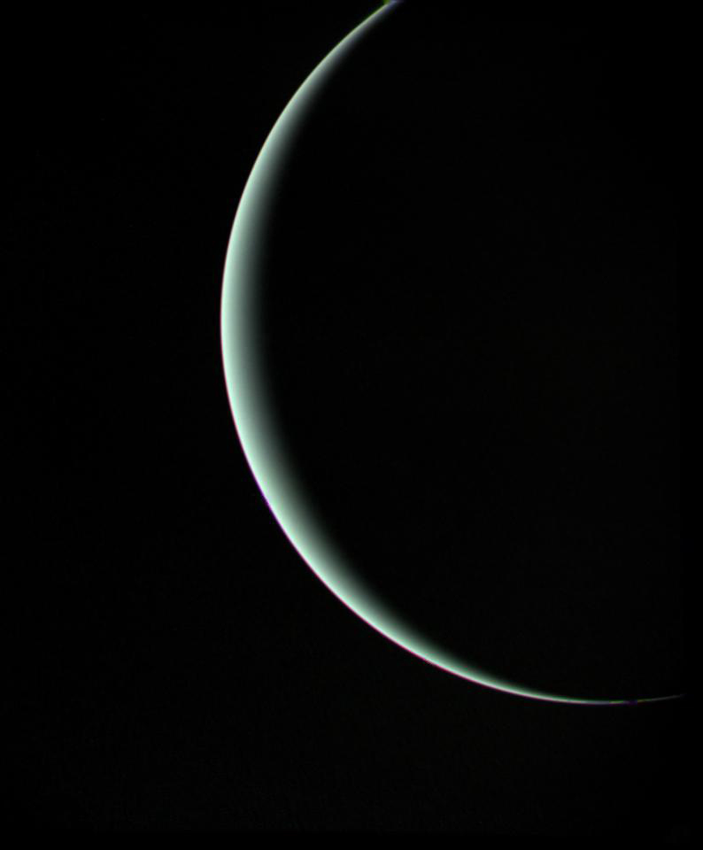 La media luna de Urano iluminada por la luz solar contrasta con el fondo negro del espacio.