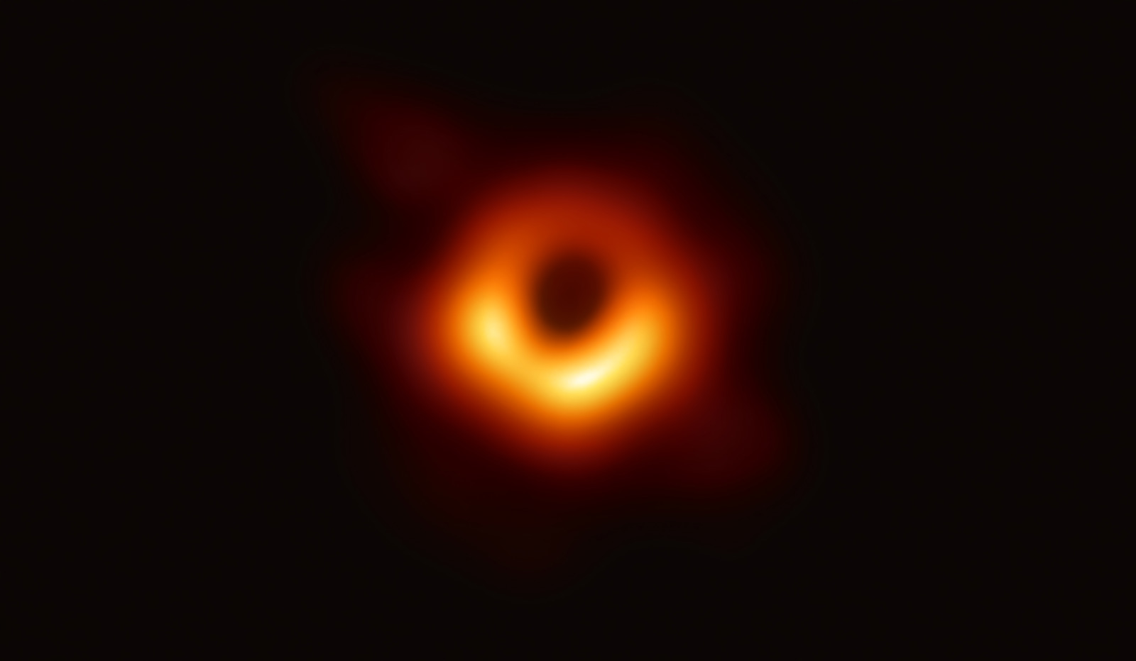 Dark spot of a black hole ringed with bright orange light.