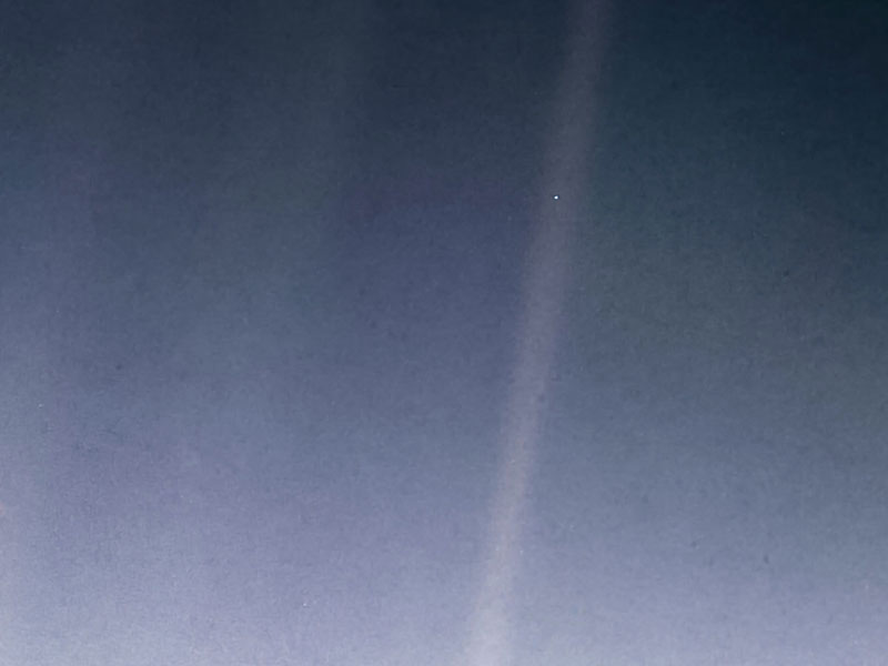 Earth seen as a small dot suspended in a grainy beam of sunlight
