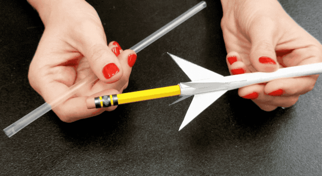 Animated GIF of a woman removing a pencil from a paper rocket and inserting a straw for launch
