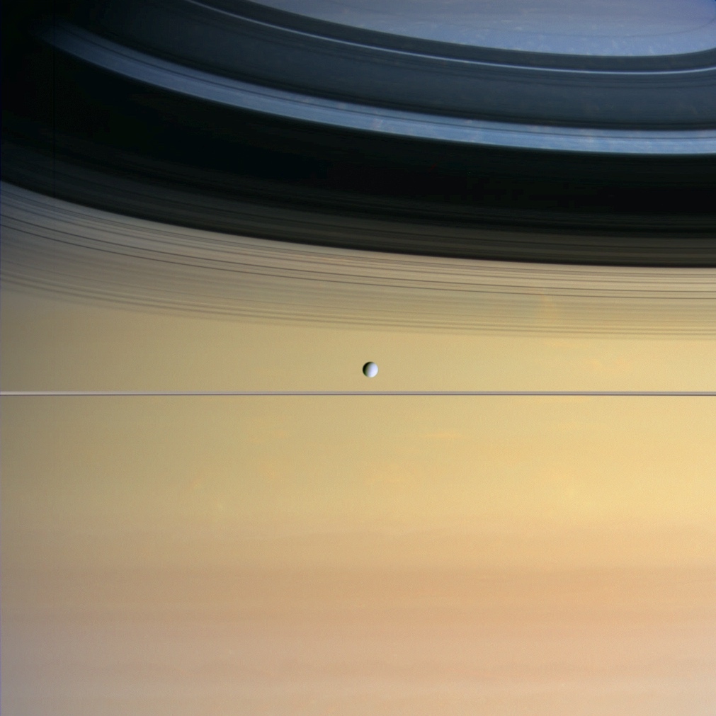 moon floating before immense face of Saturn