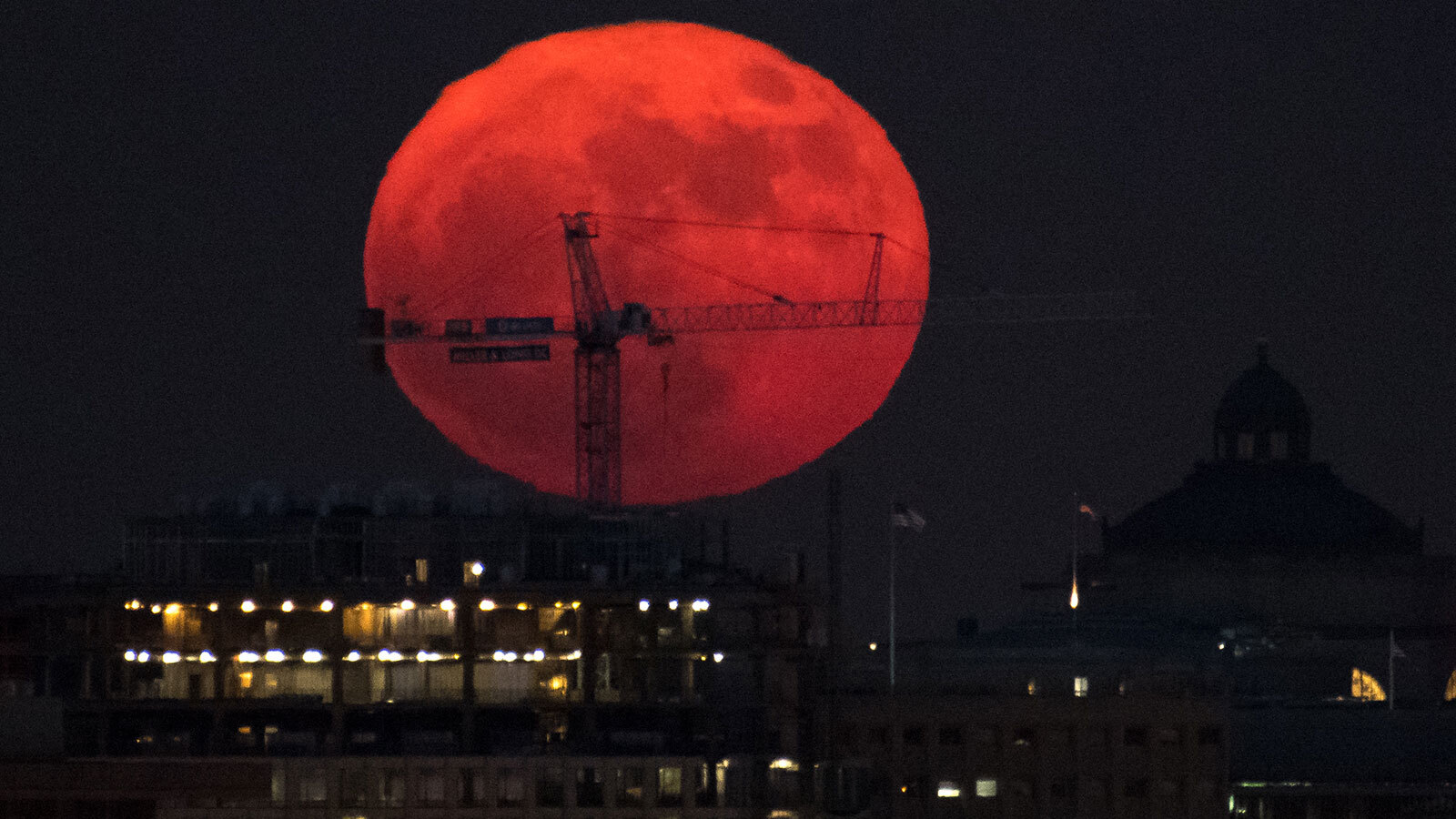 Grande Luna arancione che sorge dietro una gru sullo skyline di Washington, DC.