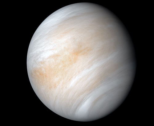 Full view of Venus enhanced to reveal swirling, pale brownish clouds.
