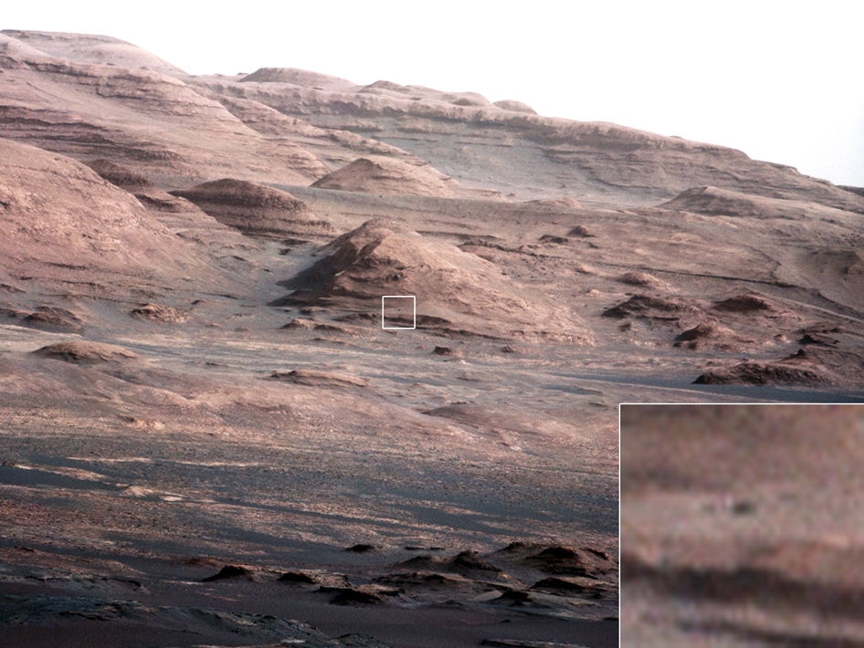 Overlapping ridges and layers ranging in color from very light to very dark brown. All slope downward from left to right. A relatively small-seeming rock at the center of the image is replicated at a larger scale in an inset.