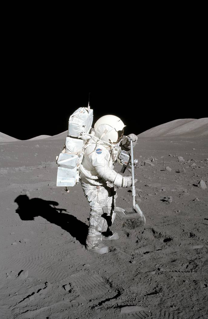 An astronaut standing with shovel poised above the lunar surface. 