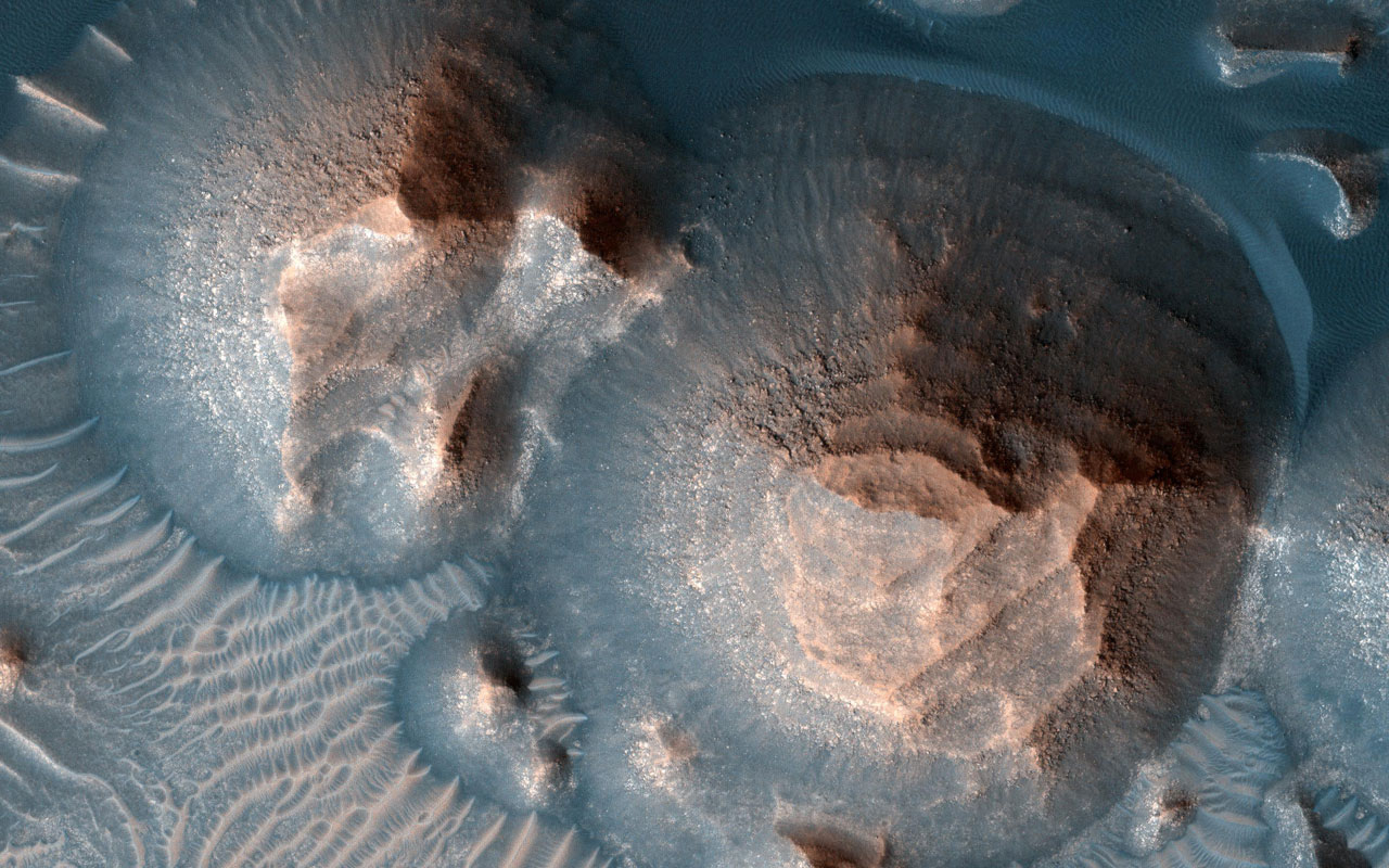 Orbital image of an ancient Martian volcano surrounded by sand dunes.