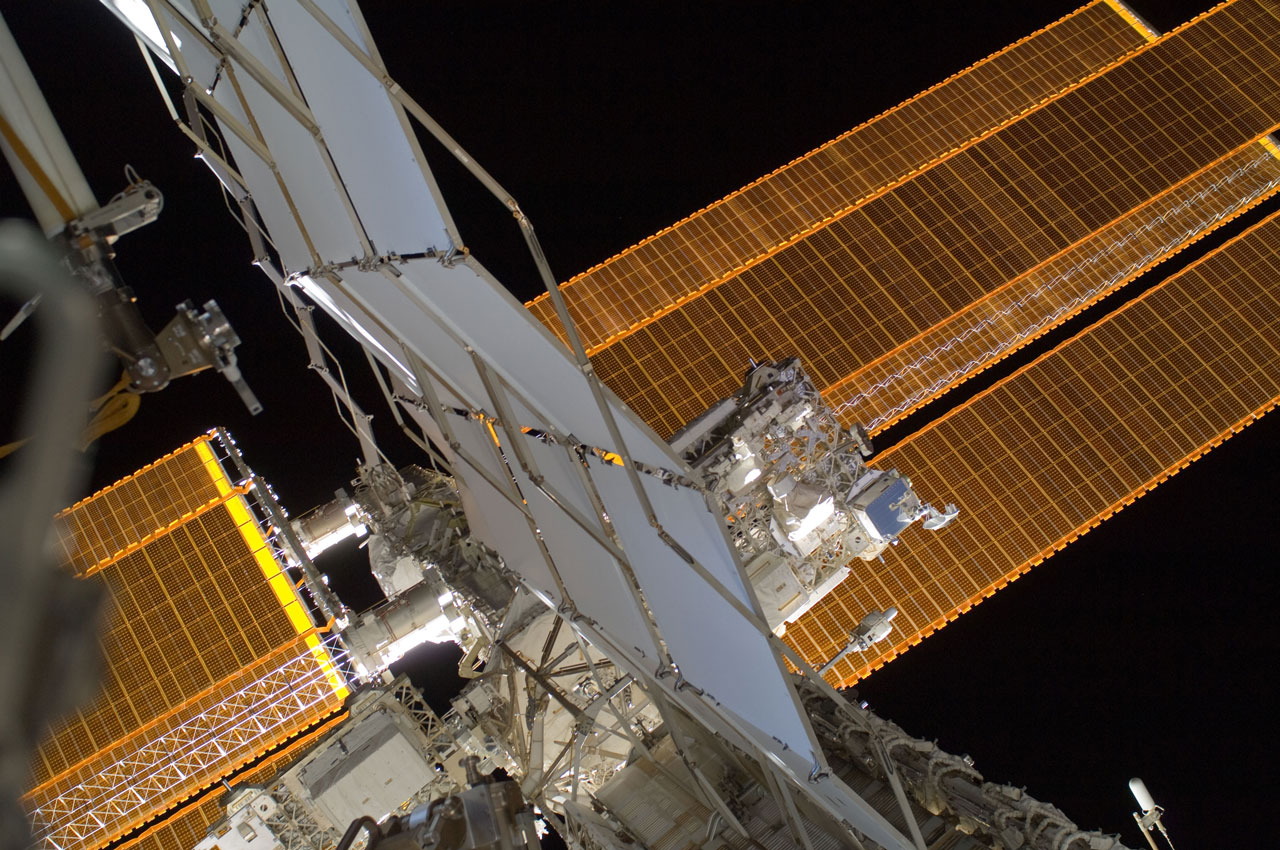 Picture of space experiment mounted outside the International Space Station with solar panels in background.