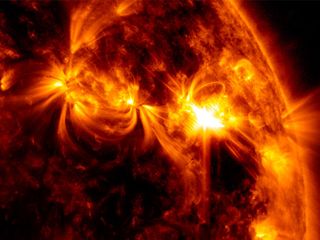 A solar flare erupts of the right side of the Sun, seen in orange in this image from the Solar Dynamics Observatory.