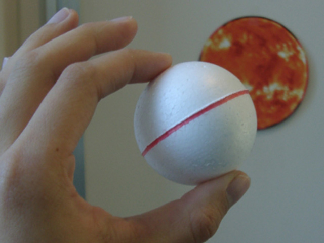 hand holding a styrofoam ball as part of an eclipse activity