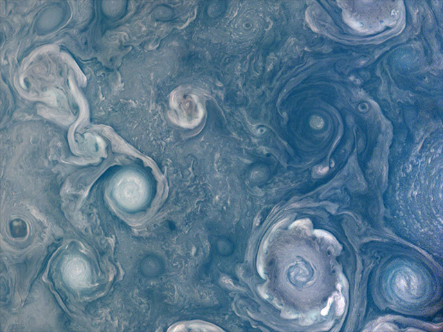 Hurricane-like spiral wind patterns of blue, purple, and white on Jupiter