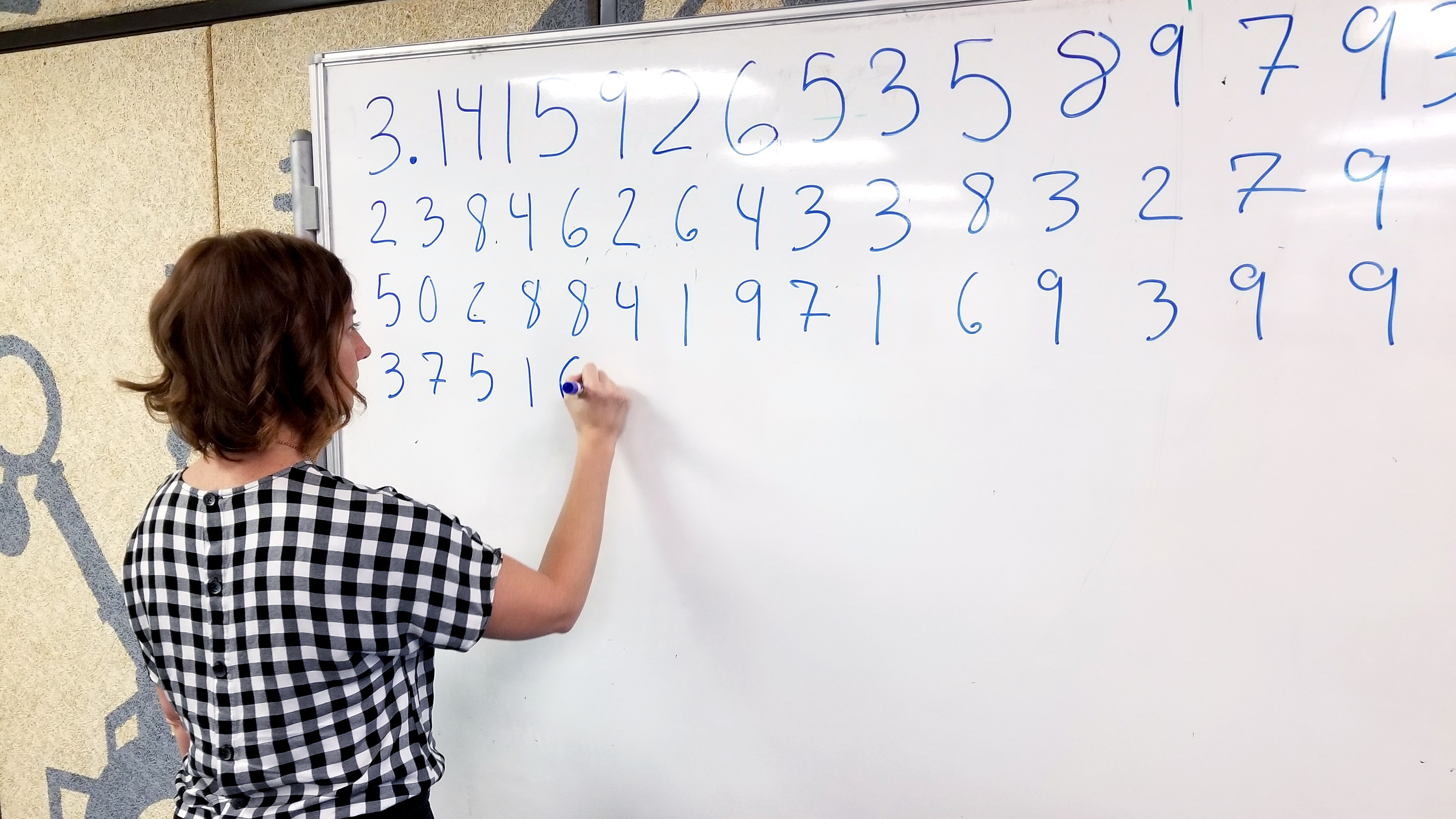 Woman writing Pi on whiteboard