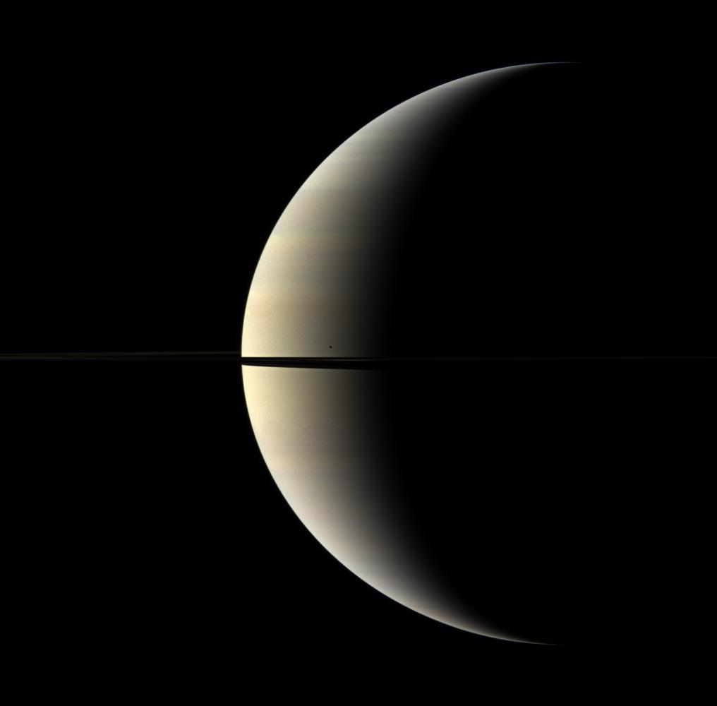 A pastel crescent of Saturn is interrupted by the moon Mimas and the rings in this color image