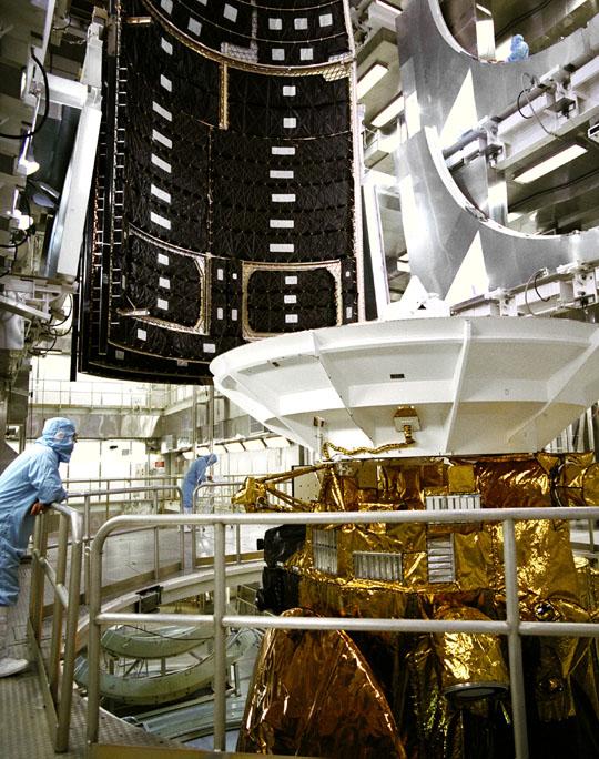 Color image of man standing next to top of spacecraft.