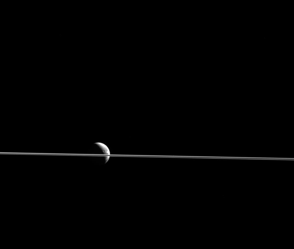 Black and white image of moon Dione divided by Saturn
