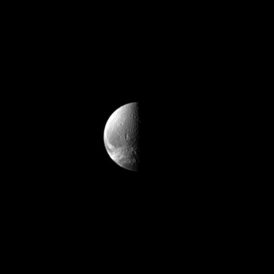 Looking down toward the north pole of the moon Dione, the Cassini spacecraft sights wispy features.