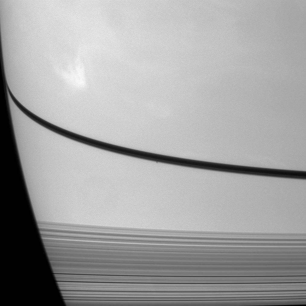 Prometheus' shadow is a small dark dot on Saturn just below the narrow shadow cast by the rings