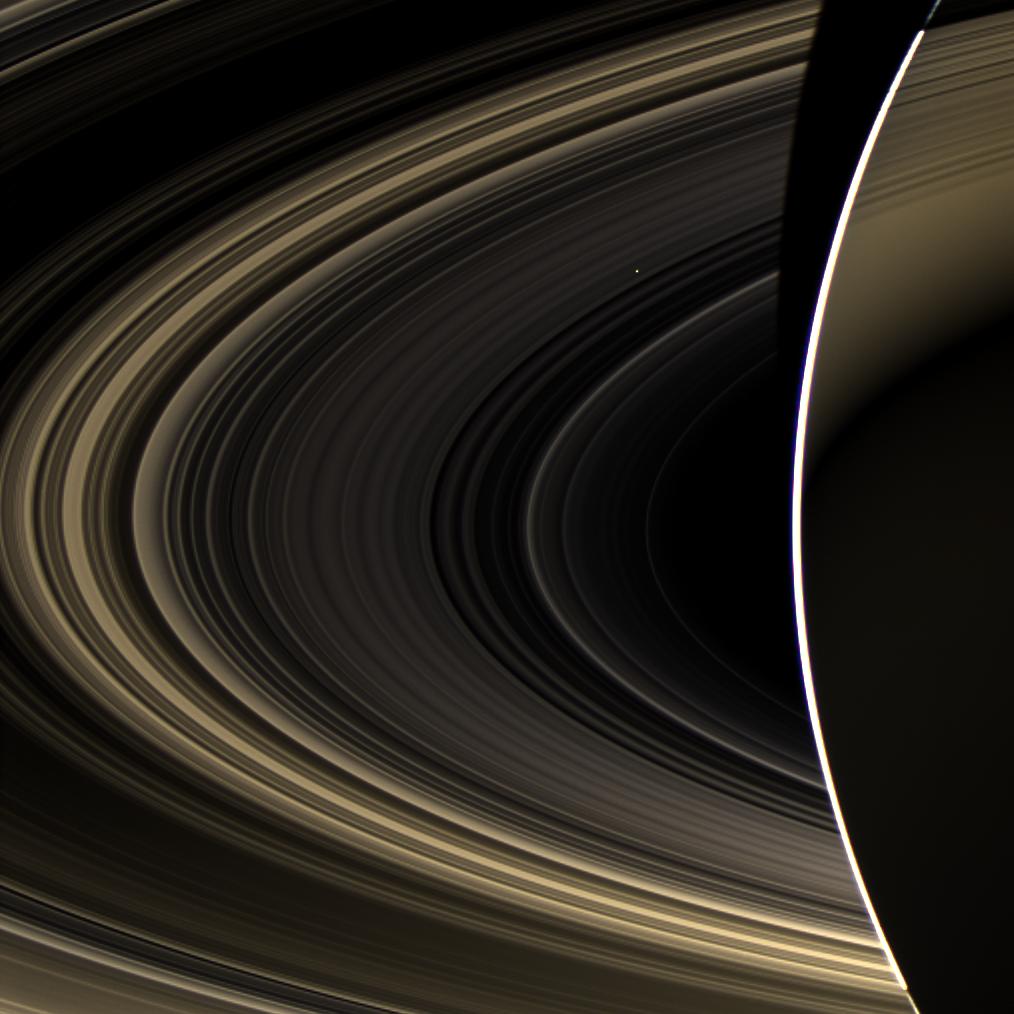 Peering over the shoulder of giant Saturn, through its rings, and across interplanetary space, NASA's Cassini spacecraft spies the bright, cloudy terrestrial planet, Venus. 