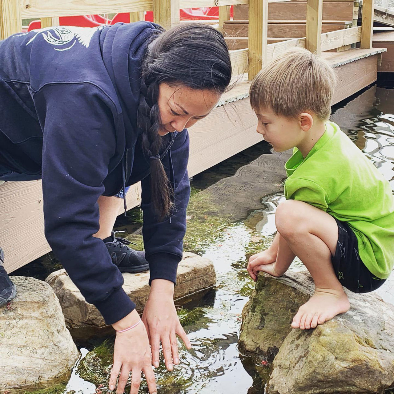 Kim playing with a little boy in a rocky stream.