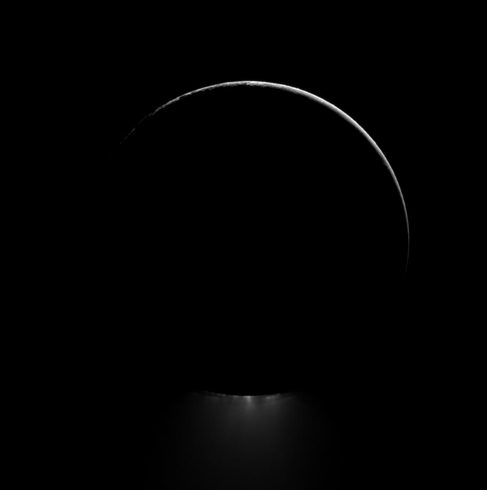 Below a darkened Enceladus, a plume of water ice is backlit in this view of one of Saturn's most dramatic moons.