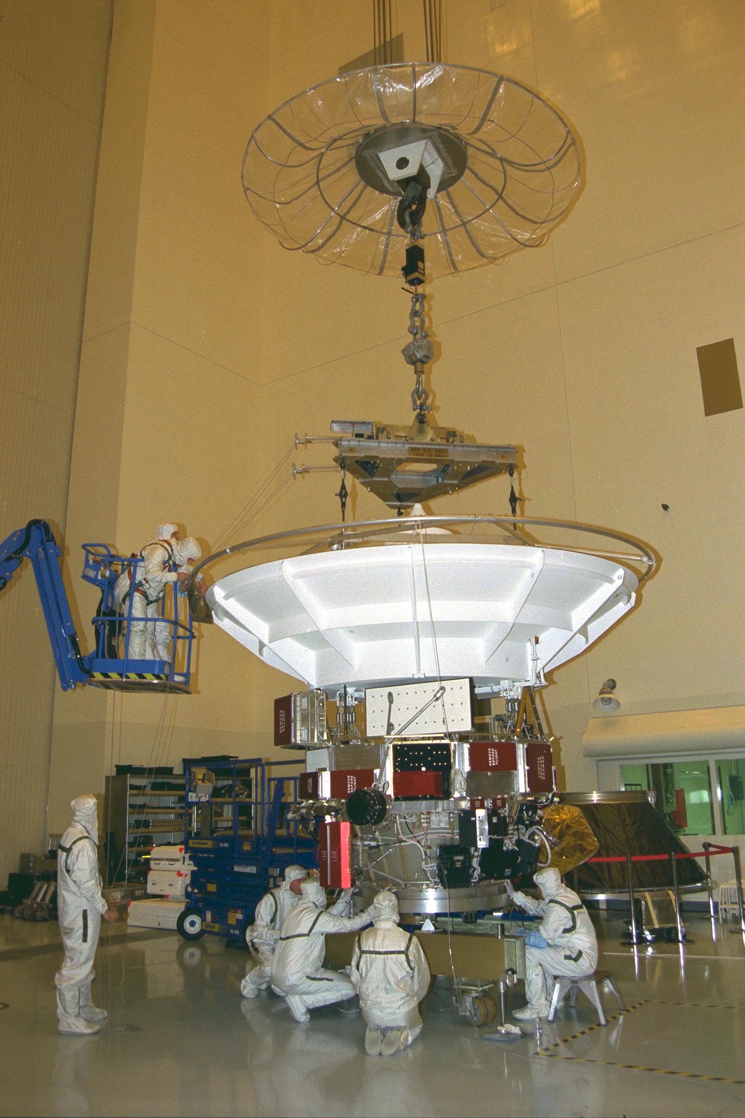 Engineers gathered around half a spacecraft.