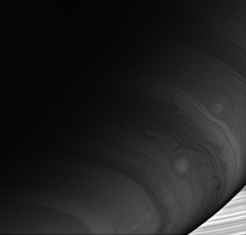 Two bright vortices roll across the cloud-lined face of Saturn