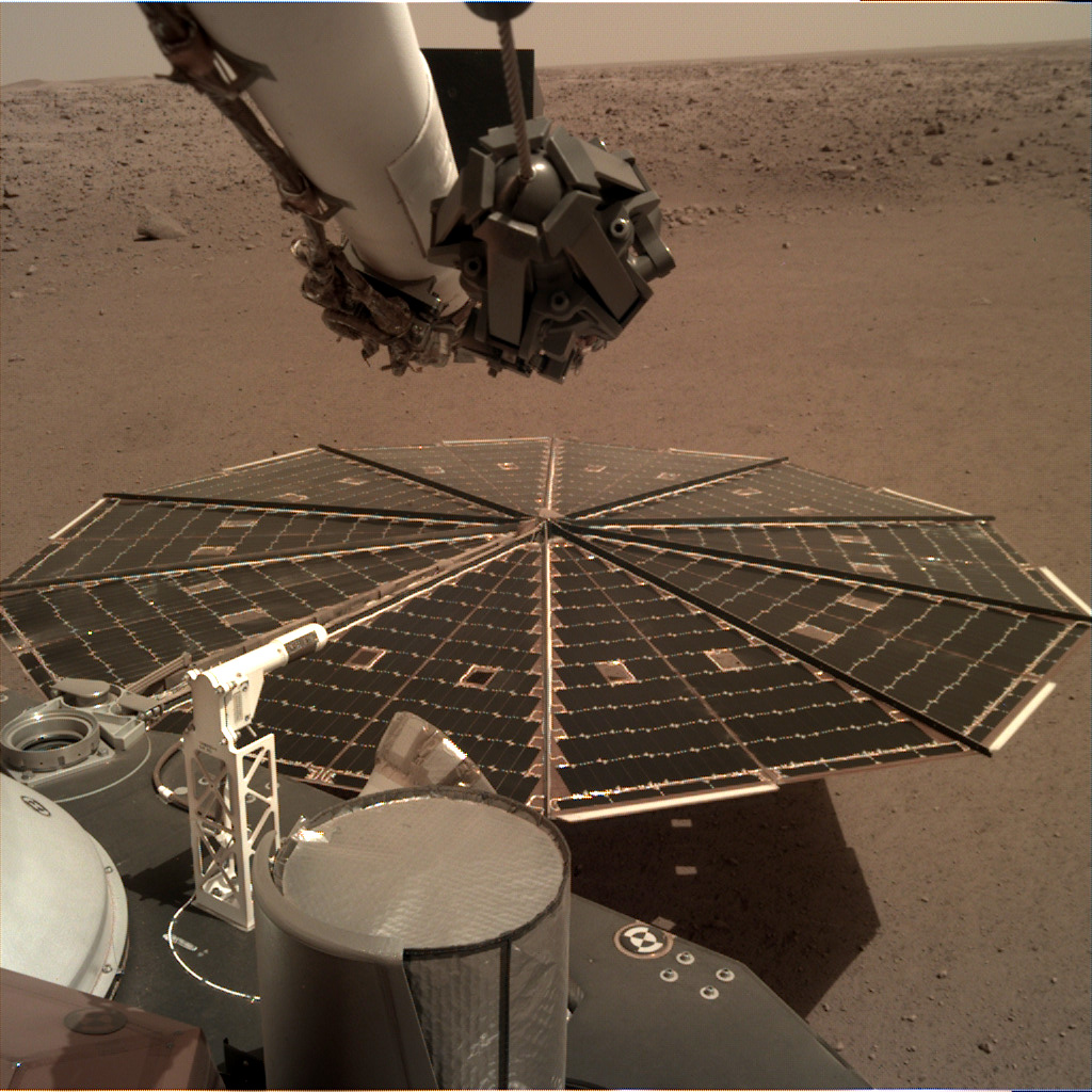 Round solar panel expanded over dusty red Martian plain.