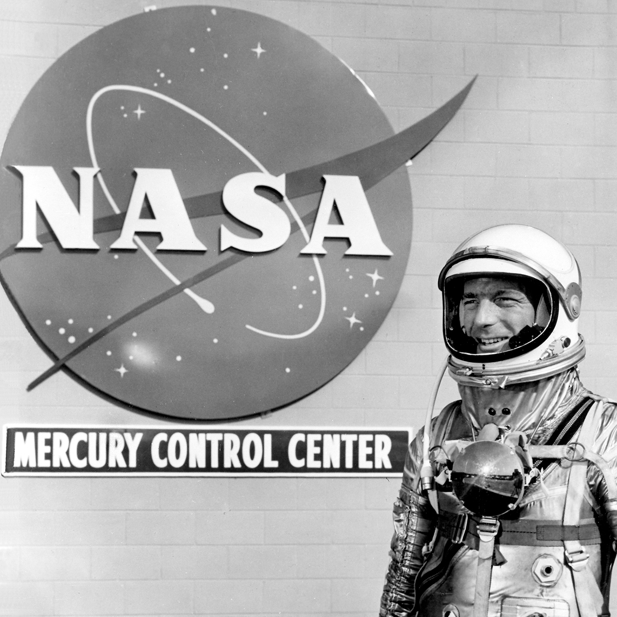 Mercury astronaut Scott Carpenter stands in front of the NASA insignia at Cape Canaveral.