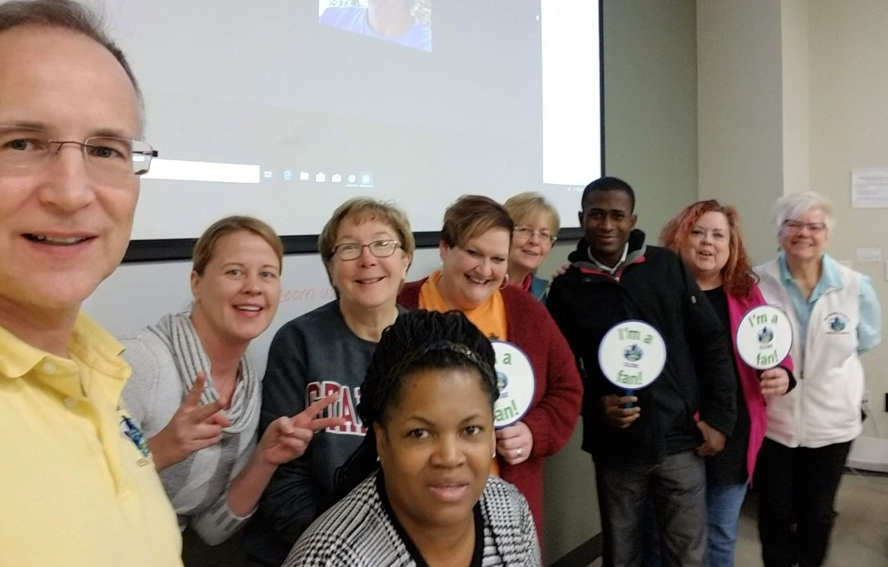 Kevin, wearing a yellow shirt and glasses, is in the foreground of this GLOBE team selfie with eight colleagues.