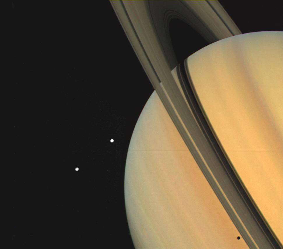 Color image of Saturn, its rings and two moons, Tethys and Dione.