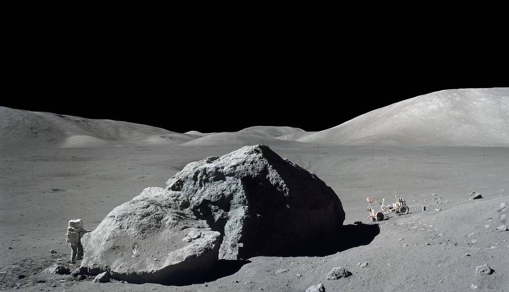 Astronaut on the moon with lunar boulder