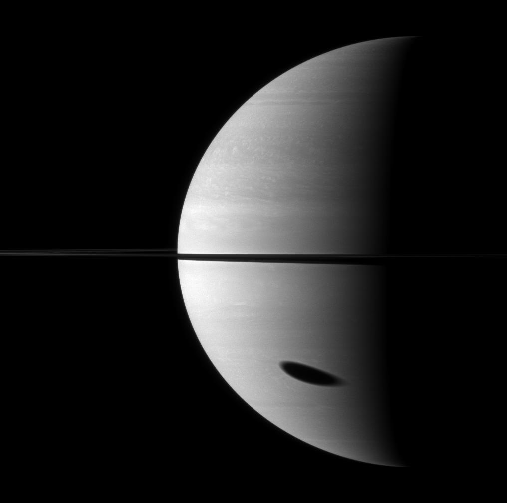 The shadow of Saturn's largest moon darkens a huge portion of the gas giant planet.