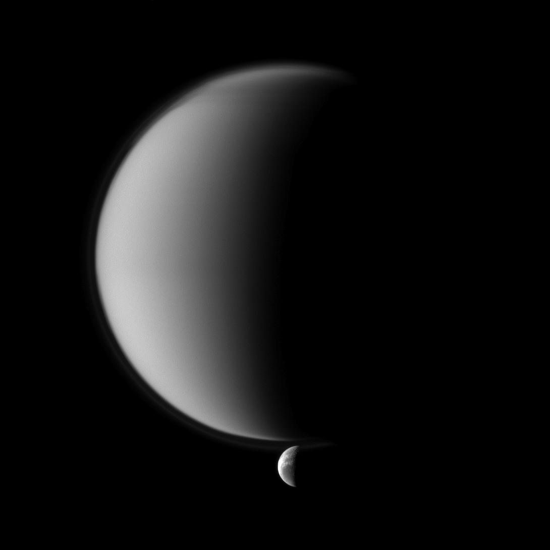 Crisp details on Dione contrast with the haziness of Titan in this Cassini spacecraft image of a pair of Saturn's moons.