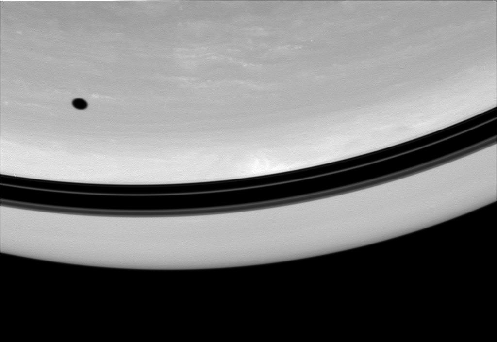 The shadow of Tethys drifts across the face of Saturn