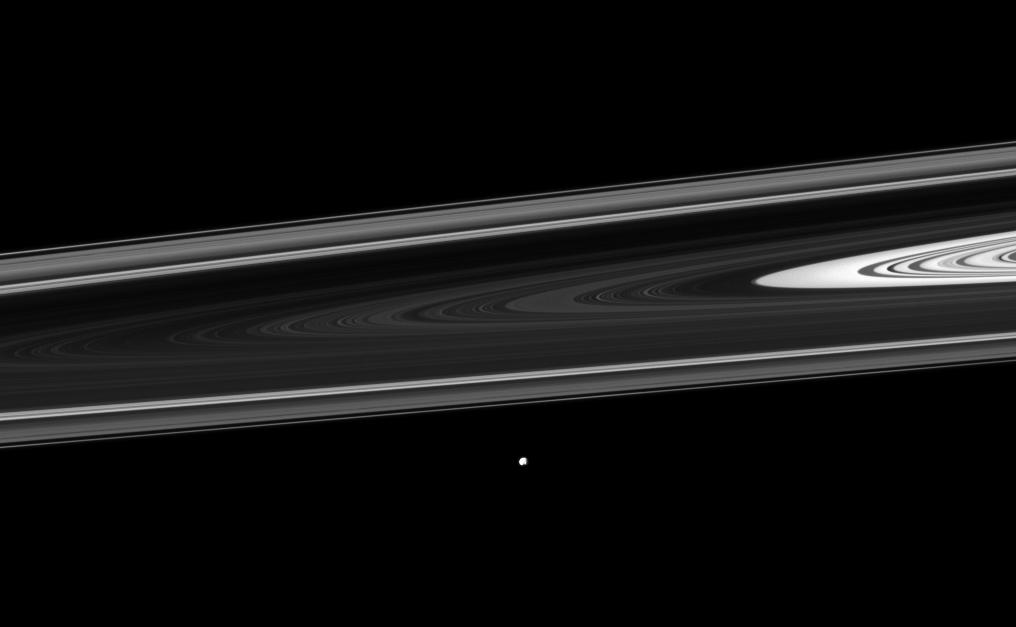 The Cassini spacecraft watches Saturn's small moon Epimetheus orbiting beyond the planet's rings.