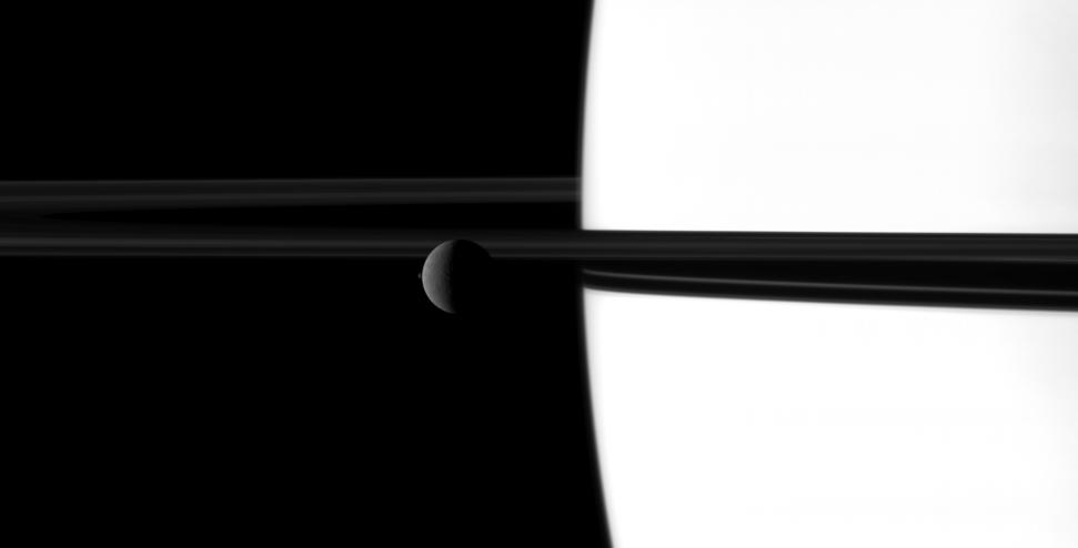 The small moon Janus overtakes the larger moon Rhea in a dance played out before Saturn and its rings.