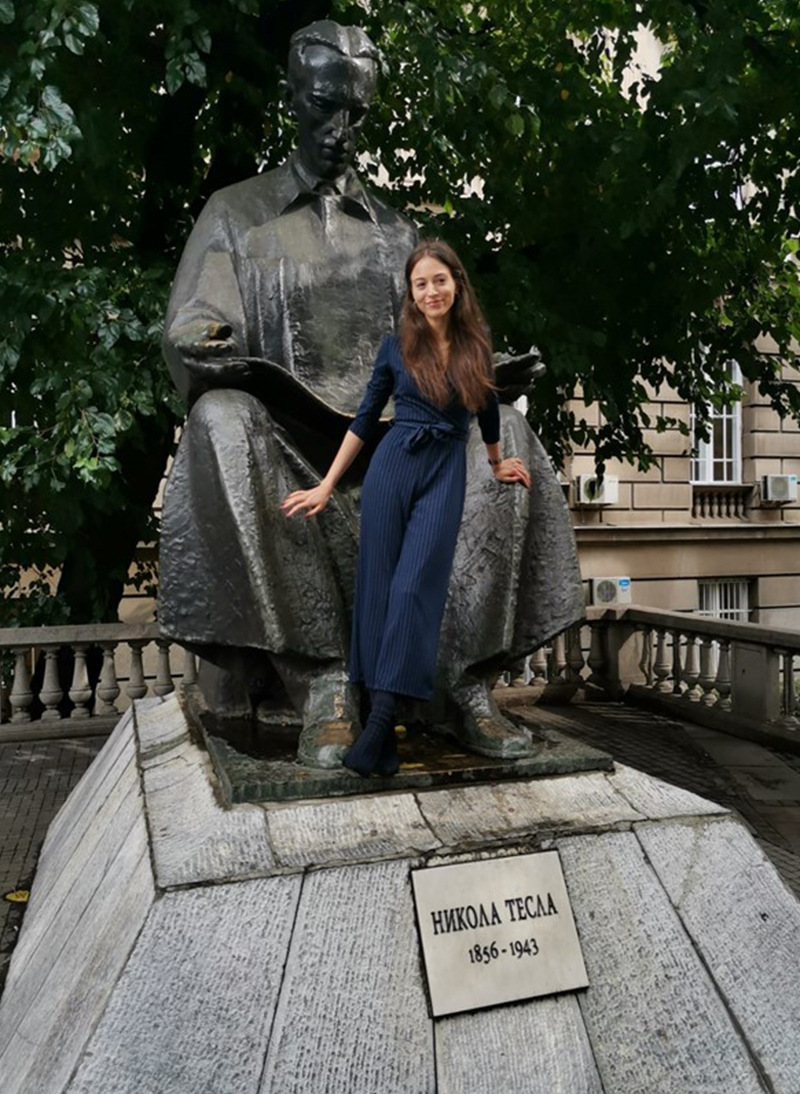 Tamara Stajić strikes a confident pose with a giant statue of Nikola Telsa. 