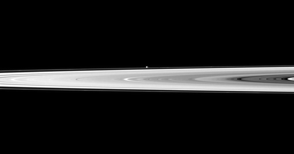 The tiny moon Pandora appears beyond the bright disk of Saturn's rings.