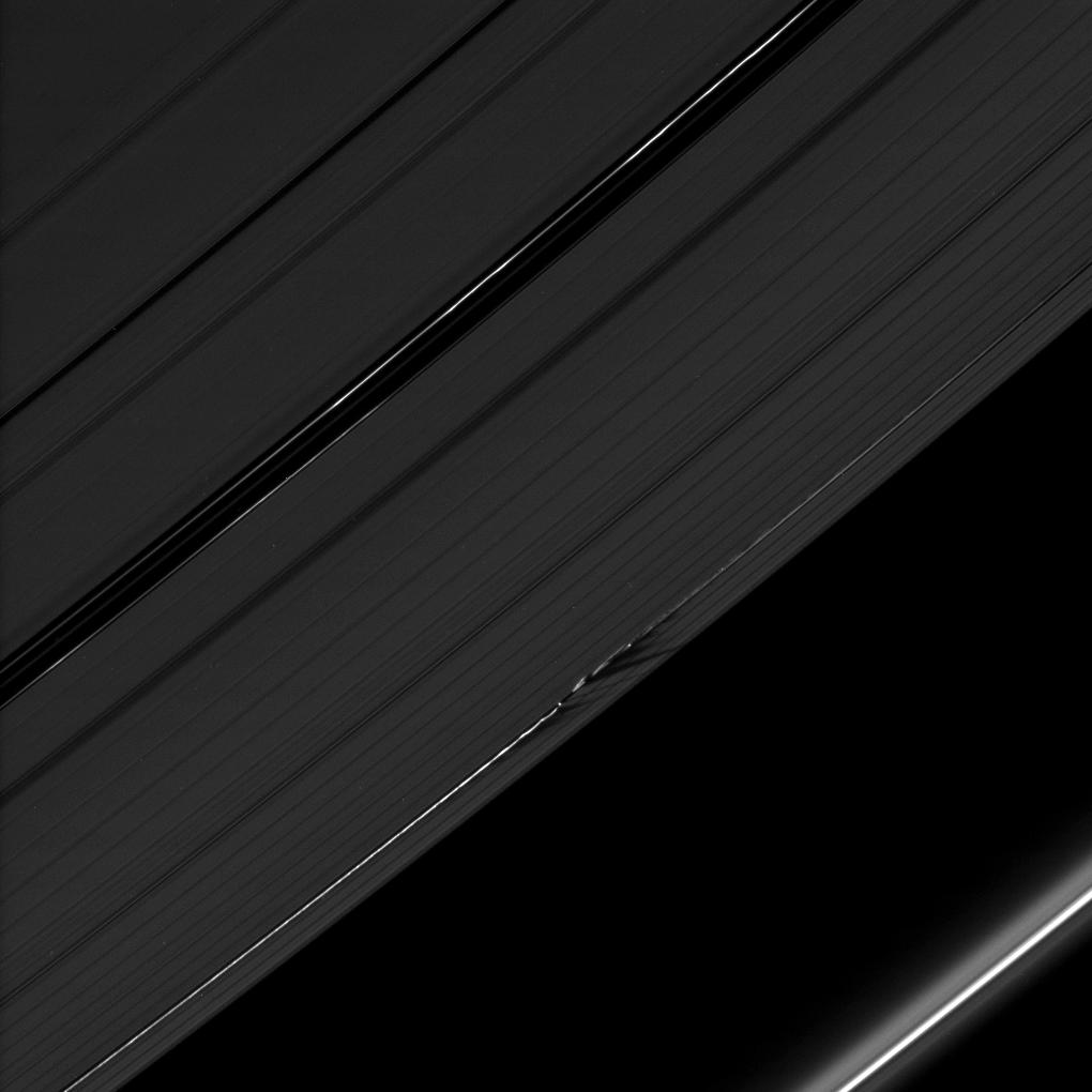 The shadows cast by Daphnis' attendant edge waves create a dark, jagged pattern on the A ring