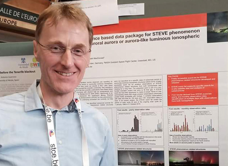 Michael standing in front of a science poster showing data readouts and summary text.