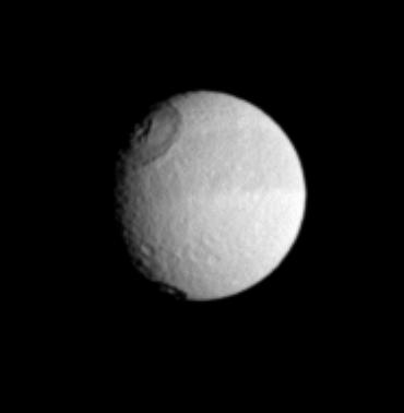 Saturn's moon Tethys displays its distinctive dark equatorial band here, along with two sizeable impact craters in the west.